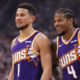 "Phoenix Suns basketball players standing on court during game in UHD quality, wearing purple jerseys with crowd background"