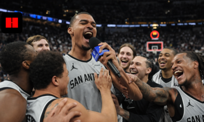 San Antonio Spurs players celebrating together during emotional post-game interview with microphone in packed NBA arena captured from unique camera angle