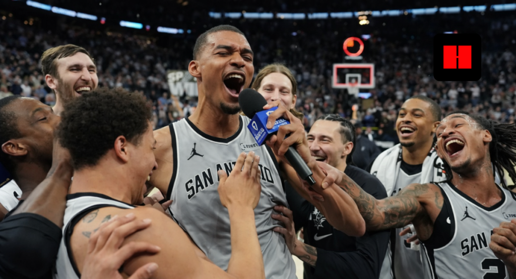 San Antonio Spurs players celebrating emotional post-game victory while giving live interview on court in packed NBA arena.