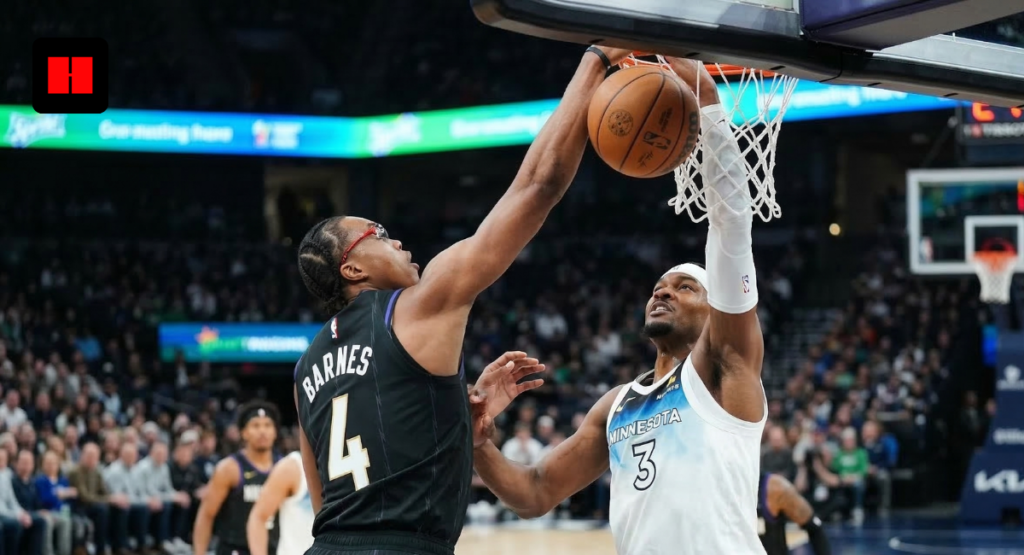 Toronto Raptors forward Scottie Barnes leaping for a dunk against a Minnesota Timberwolves defender, captured from a sideline mid-court camera angle.