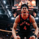 Toronto Raptors player Scottie Barnes shouting in celebration on the basketball court, low-angle action shot with arena crowd in background.