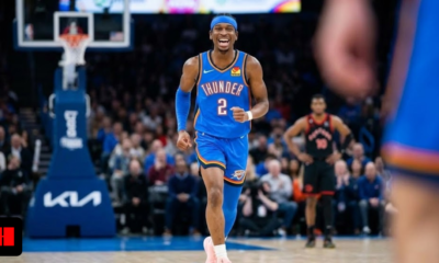 Shai Gilgeous-Alexander wearing a blue Oklahoma City Thunder jersey celebrating on the basketball court during an NBA game.