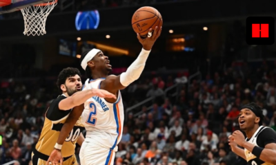 Shai Gilgeous-Alexander of the Oklahoma City Thunder driving for a layup against the Washington Wizards defense in a crowded NBA arena.