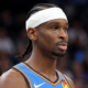 Close-up portrait of Shai Gilgeous-Alexander wearing a blue Oklahoma City Thunder jersey and white headband during a game.