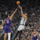 San Antonio Spurs player attempts jump shot over Phoenix Suns defender during intense NBA game action in crowded arena.