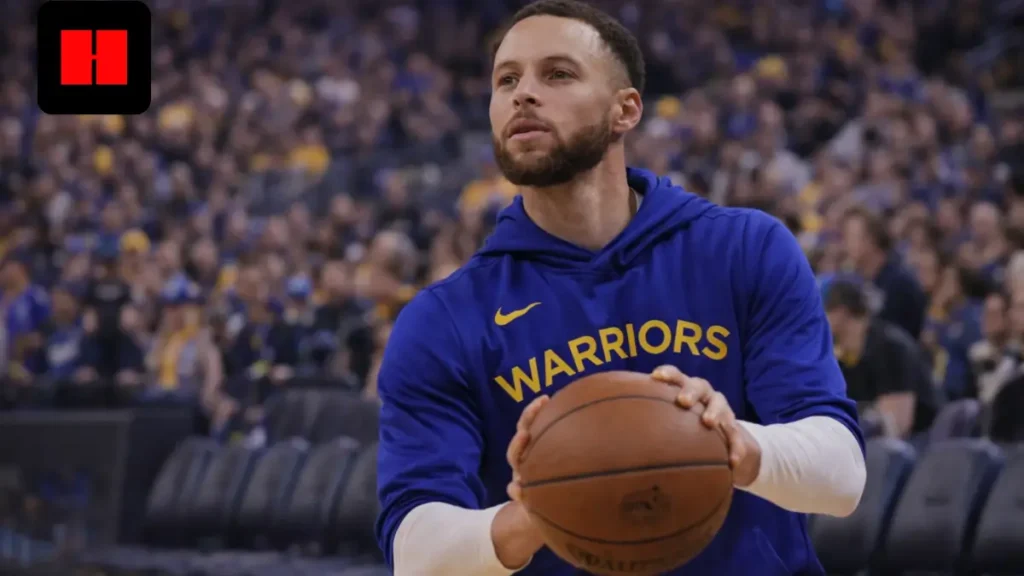 Stephen Curry warming up with a basketball while wearing a Golden State Warriors hoodie before a game.