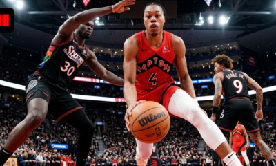 Intense wide-angle action shot of Toronto Raptors player Scottie Barnes driving to the basket during a game against the Philadelphia 76ers.