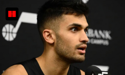 Utah Jazz basketball player speaking during a press conference interview with team logo visible in the background.