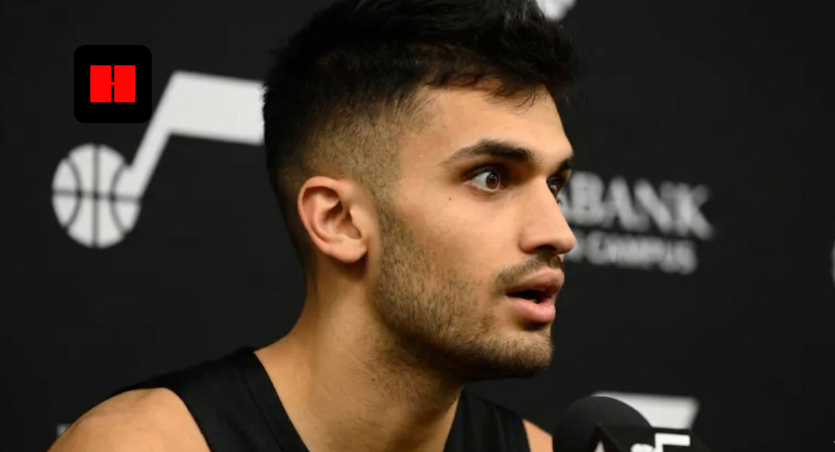 Utah Jazz basketball player speaking during a press conference interview with team logo visible in the background.