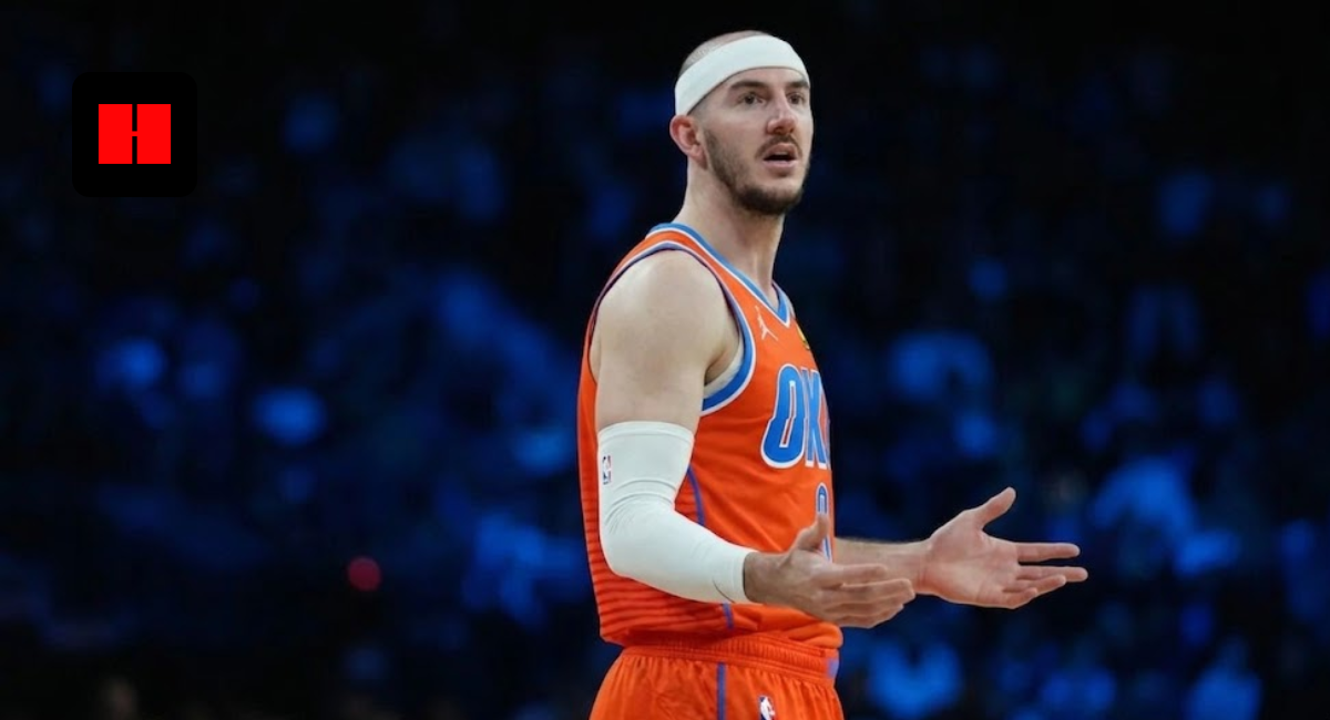 Alex Caruso of the Oklahoma City Thunder wearing an orange jersey and white headband, gesturing with his hands during a basketball game with a blurred arena background.