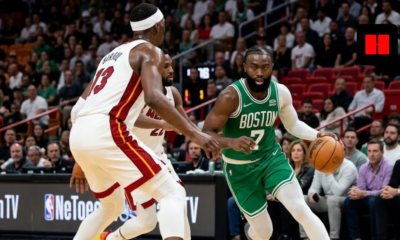 Jaylen Brown of the Boston Celtics dribbling the basketball past Bam Adebayo during an NBA game against the Miami Heat.