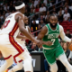 Jaylen Brown of the Boston Celtics dribbling the basketball past Bam Adebayo during an NBA game against the Miami Heat.