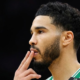 Jayson Tatum of the Boston Celtics in a side profile view on the basketball court, wearing a green and white jersey with fingers to his lips.