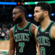 Jayson Tatum and Jaylen Brown standing together on the court in black Boston Celtics jerseys during an NBA game.