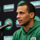 Boston Celtics head coach Joe Mazzulla speaking into a microphone during a press conference with Amica and Celtics logos in the background.