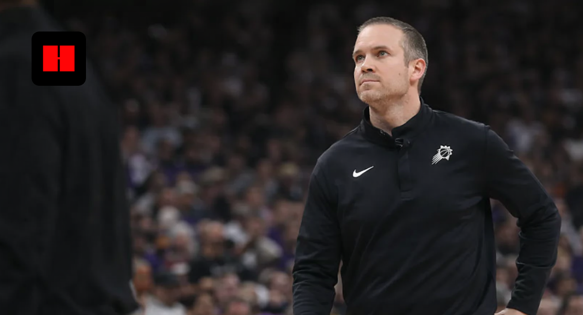 NBA coach standing courtside during Phoenix Suns game with focused expression and crowd in background