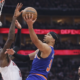 New York Knicks player attempts a layup while Houston Rockets defender tries to block during NBA game