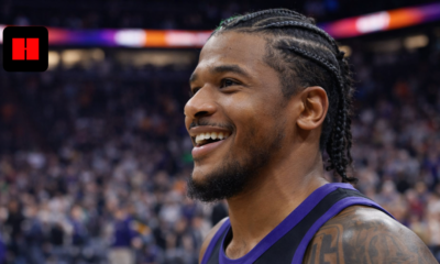 Close-up of a Phoenix Suns basketball player smiling after a game with blurred arena crowd in the background