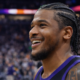 Close-up of a Phoenix Suns basketball player smiling after a game with blurred arena crowd in the background
