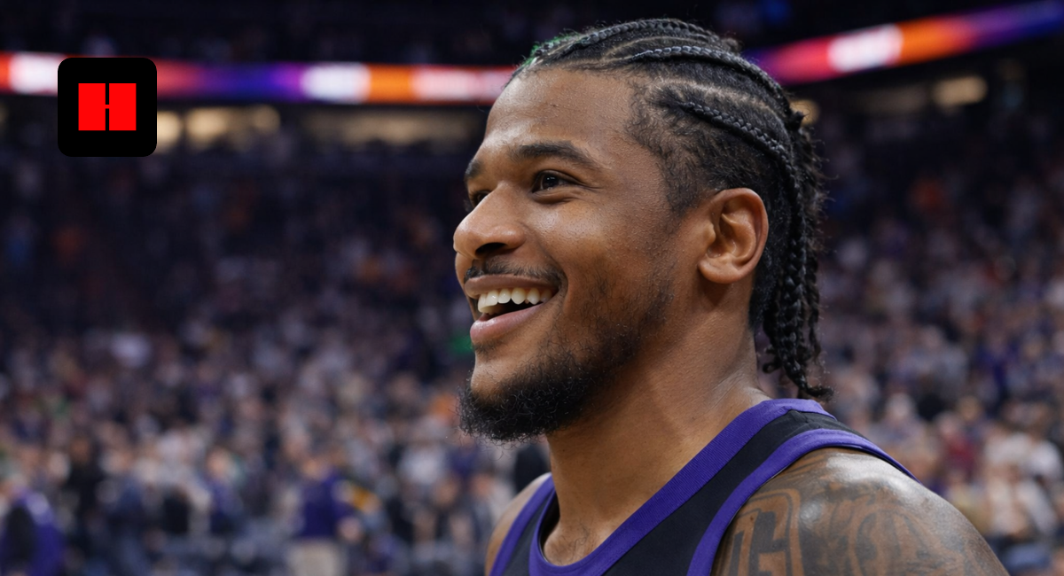 Close-up of a Phoenix Suns basketball player smiling after a game with blurred arena crowd in the background