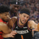 Devin Booker driving to the basket while being defended during a Phoenix Suns vs Portland Trail Blazers NBA game