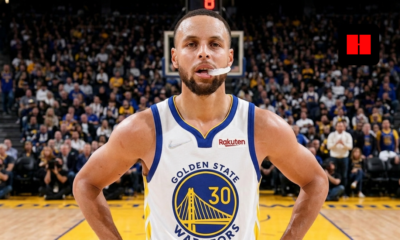 Stephen Curry standing on court in Golden State Warriors jersey with mouthguard out during home game action in 2026